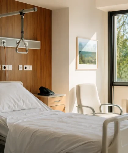 Vue d'ensemble d'une chambre individuelle d'hôpital moderne avec lit médicalisé et fenêtre lumineuse